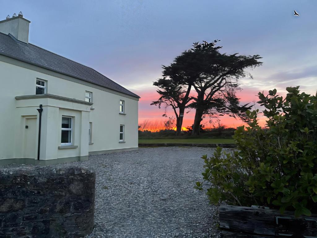 a white house with a tree and a sunset at Sanderling Lodge in Greenfield Cross Roads
