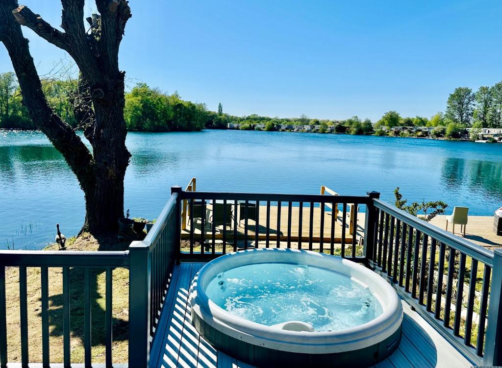 a bath tub sitting on a deck next to a river at Exclusive Lakeside Holiday Lodge with Hot tub and Private Fishing Peg at Tattershall Lakes in Tattershall