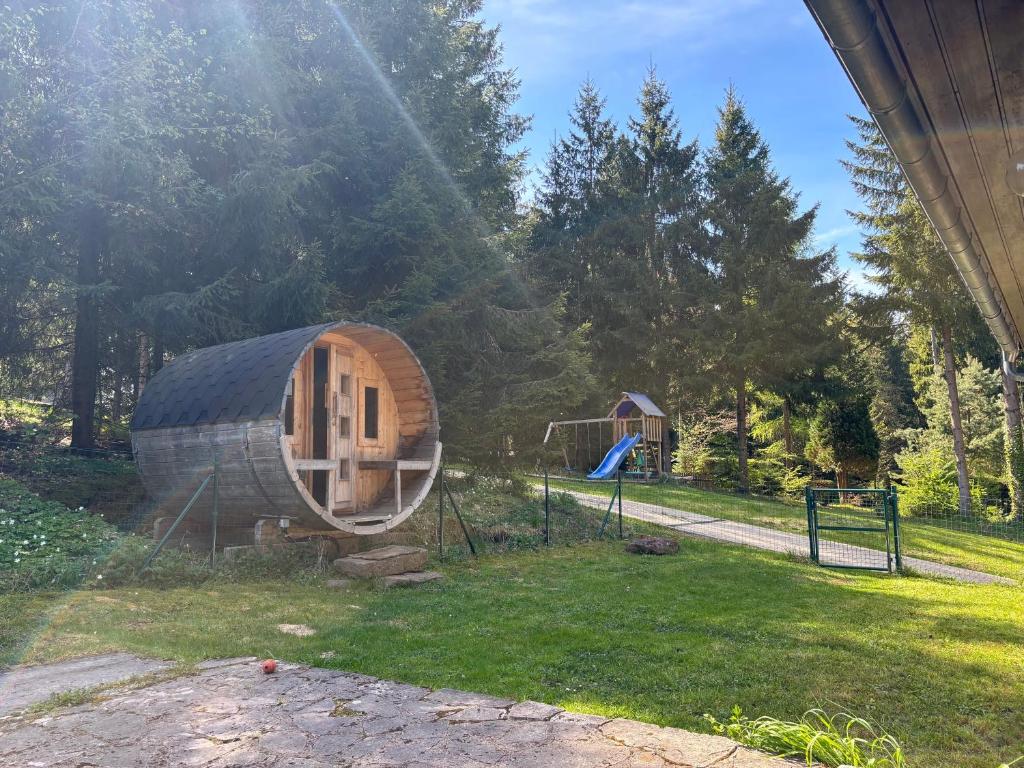 a wooden cabin in a park with a playground at Ferienhaus mit Sauna am Waldrand in Friedrichroda