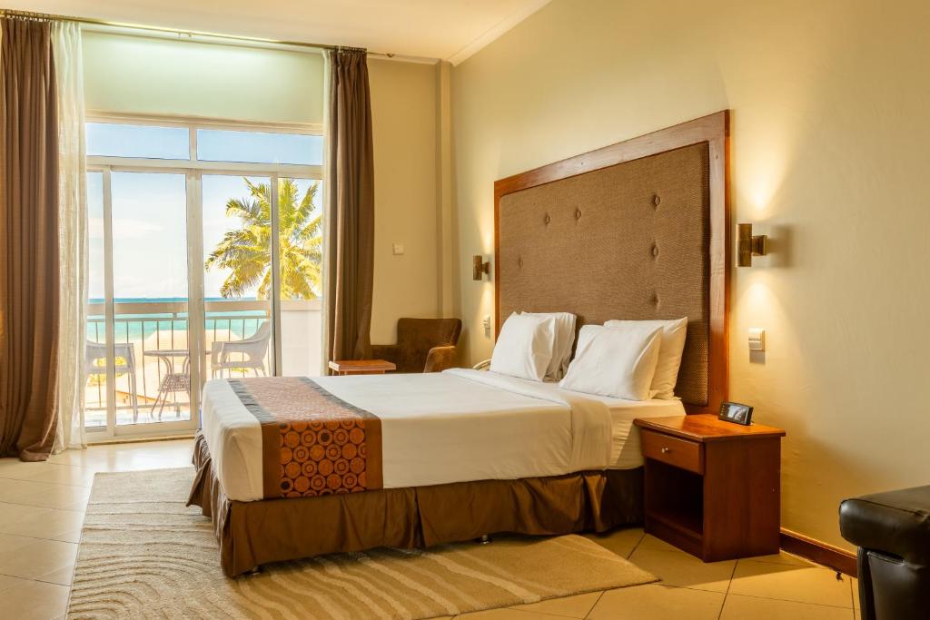 a hotel room with a large bed and a balcony at Seascape Hotel in Dar es Salaam