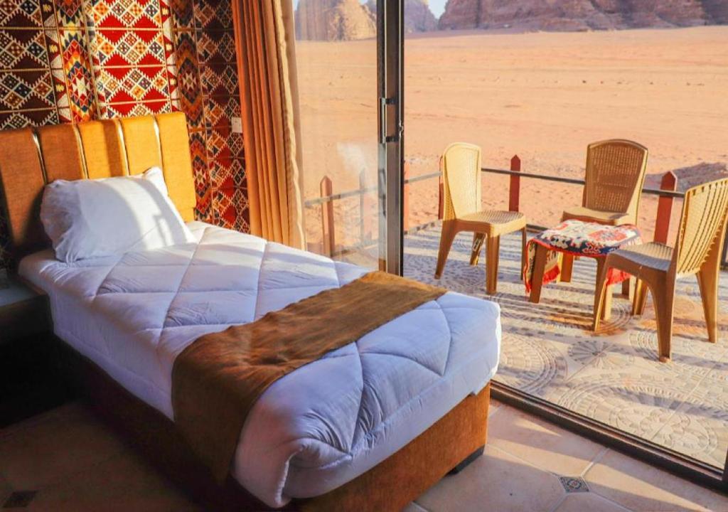 a bedroom with a bed and a balcony with a view at Rum Sky Experiences in Wadi Rum