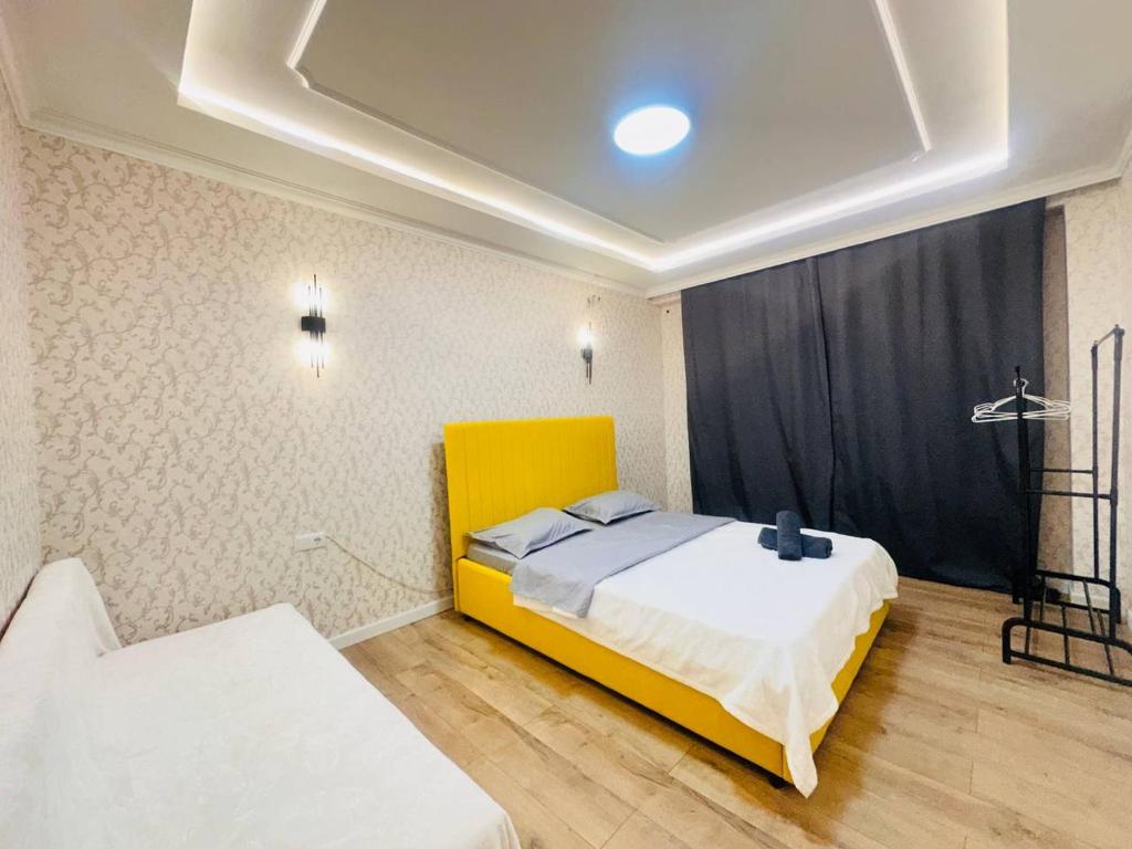 a bedroom with a yellow bed in a room at Гостевой Хаб у Сайрана 8 спальных мест у автовокзала in Almaty
