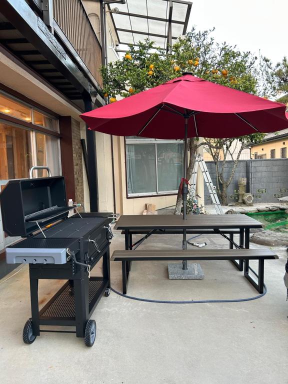 a picnic table with a grill and a red umbrella at コテージ銚子百里 in Hasaki