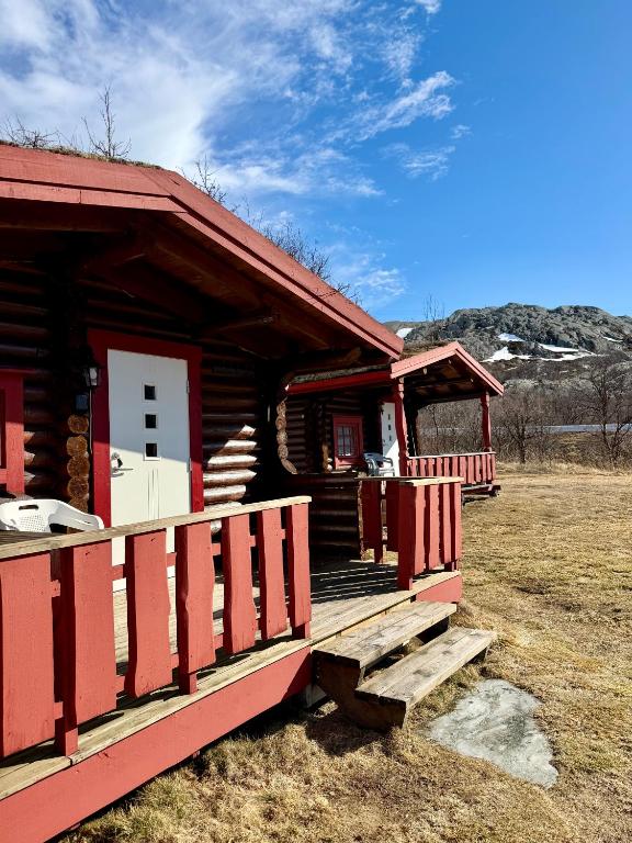 a log cabin with a porch and a white door at Grasbakken hytteutleie in Nesseby