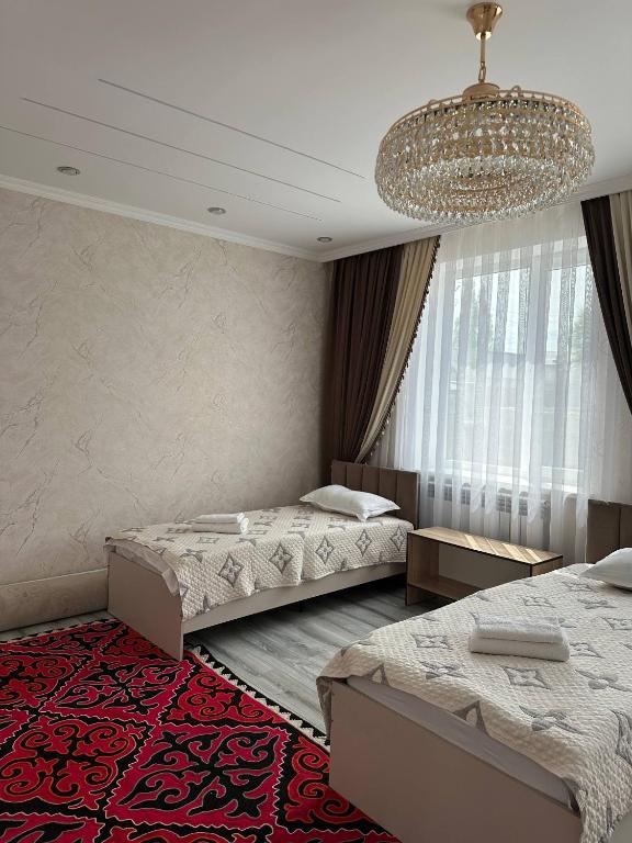 a bedroom with two beds and a chandelier at Guest hause ASEL in Kazarman