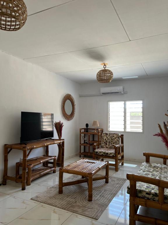 a living room with wooden furniture and a flat screen tv at Villa Mondoukou Beach in Île Bouët