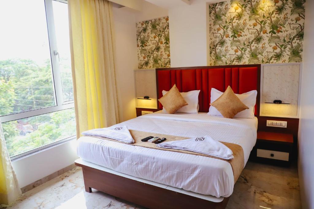 a bedroom with a bed with a red headboard and a window at Sapphire Suites in Navi Mumbai