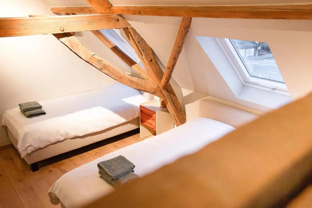 an attic room with two beds and a window at Herberg 't Molenhuis in Vichte