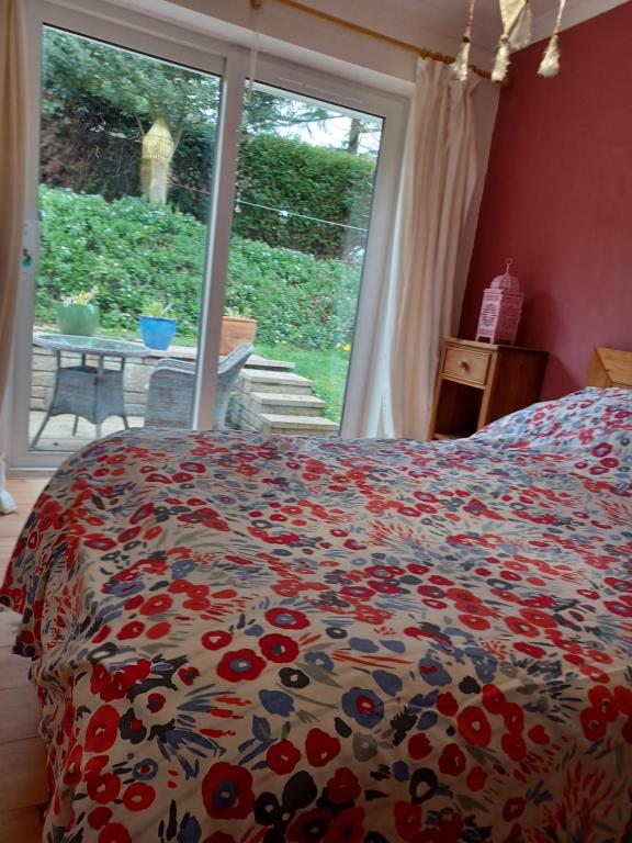 ein Schlafzimmer mit einem Bett mit einer geblümten Tagesdecke und einem Fenster in der Unterkunft Rodali in Lyme Regis