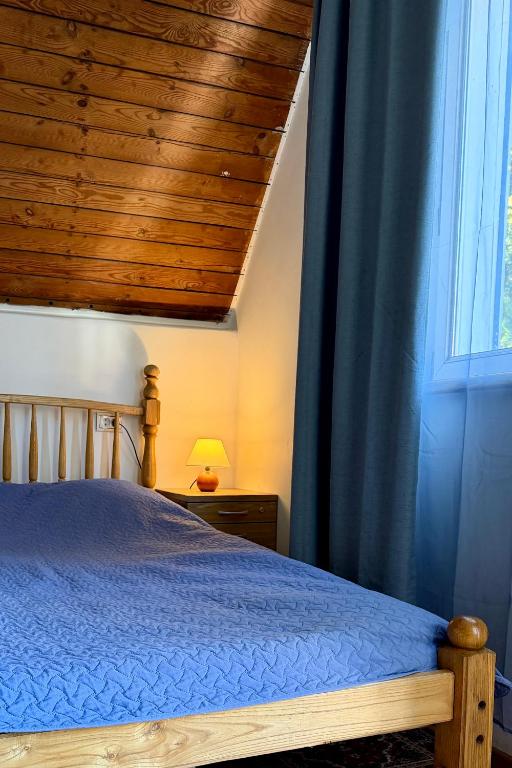 a bedroom with a bed with a wooden ceiling and a window at RestMax in Nida