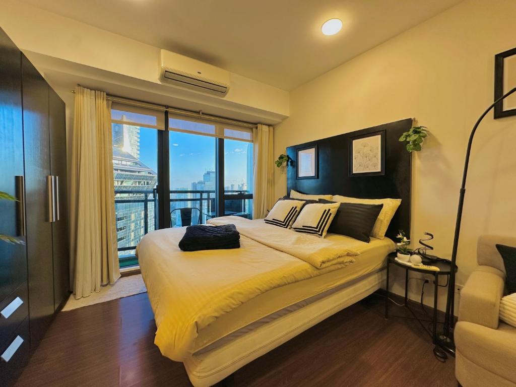 a bedroom with a large bed and a large window at Knightsbridge Residences in Manila