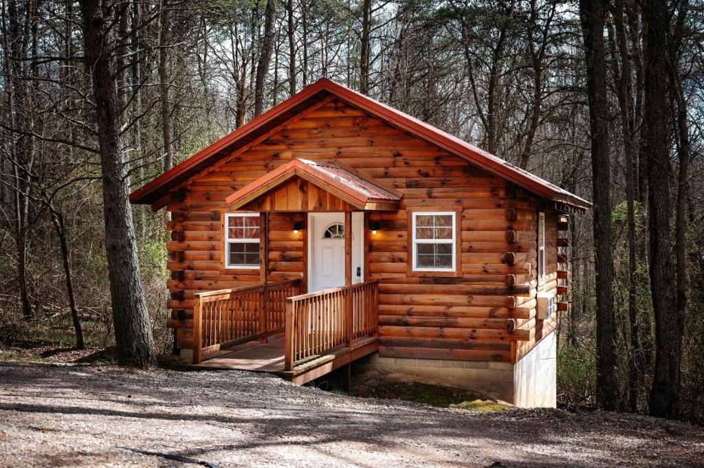 a log cabin with a porch in the woods at Cardinal's Crest in Logan