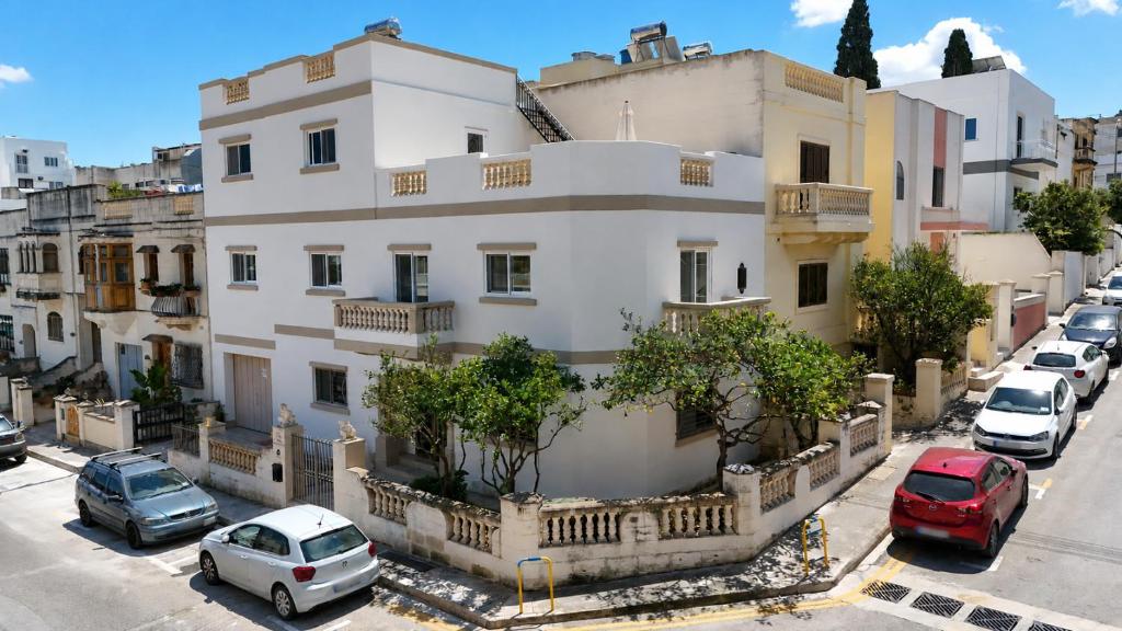 a white building with cars parked in front of it at Corner Townhouse 1Km from University in Msida