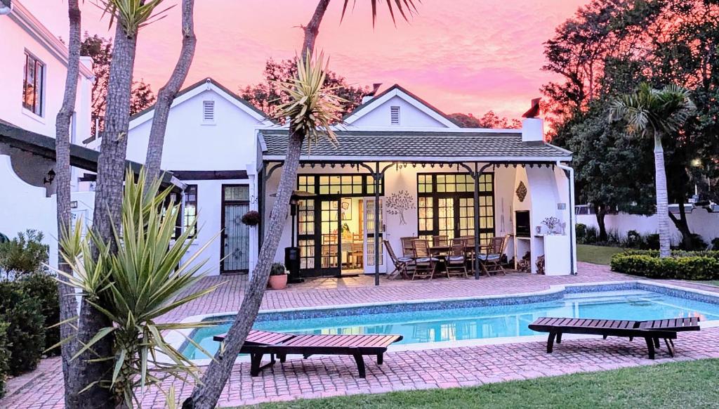 a house with a swimming pool and two benches at Whistlewood Guesthouse Walmer, Port Eizabeth in Port Elizabeth