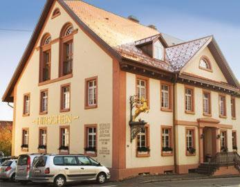 un bâtiment avec des voitures garées devant lui dans l'établissement Landgasthof Hirschen, à Albbruck