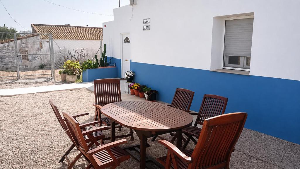 a wooden table and chairs and a table and a blue wall at Casa Carme in Camarles