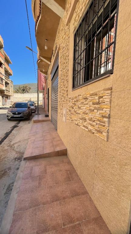 a sidewalk next to a brick building with a window at Ain El Turk Beach Apartment in Aïn El Turk