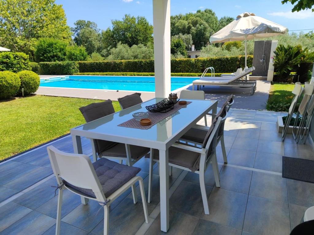 a patio with a table and chairs and a pool at Sea & Summit Pool Villa in Platamonas