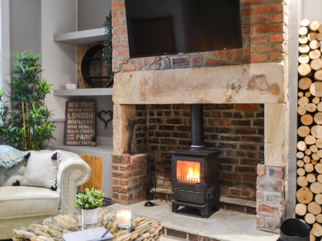 a living room with a fireplace and a tv at Copper Cottage in Morpeth