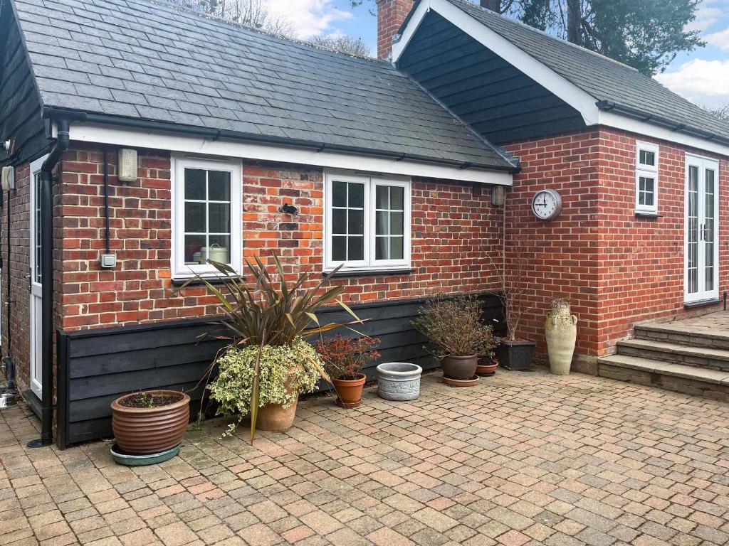 a brick house with potted plants in front of it at The Cottage in Castle Hedingham