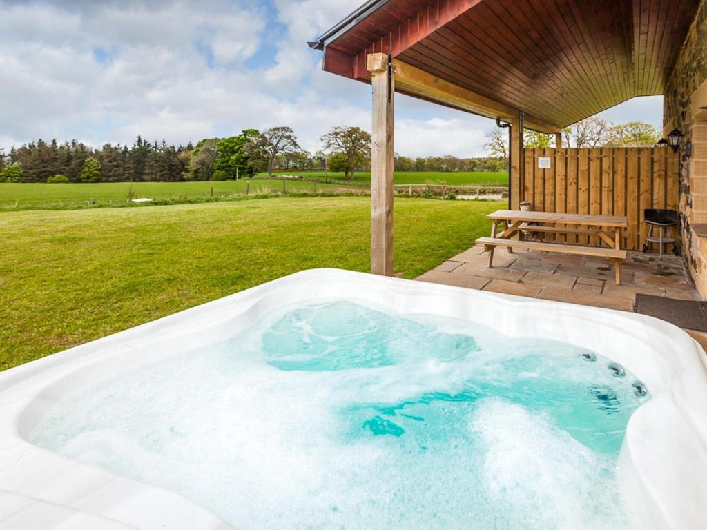 a jacuzzi tub in a yard with a bench at One Eden Cottage - Ukc6253 in Linlithgow