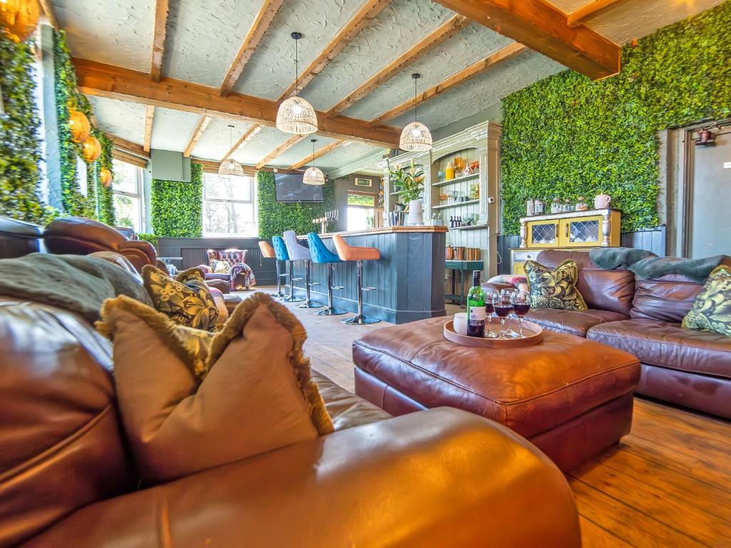 a living room with leather couches and a bar at Alderfalls - Exclusive Private Pub Experience in Coelbren
