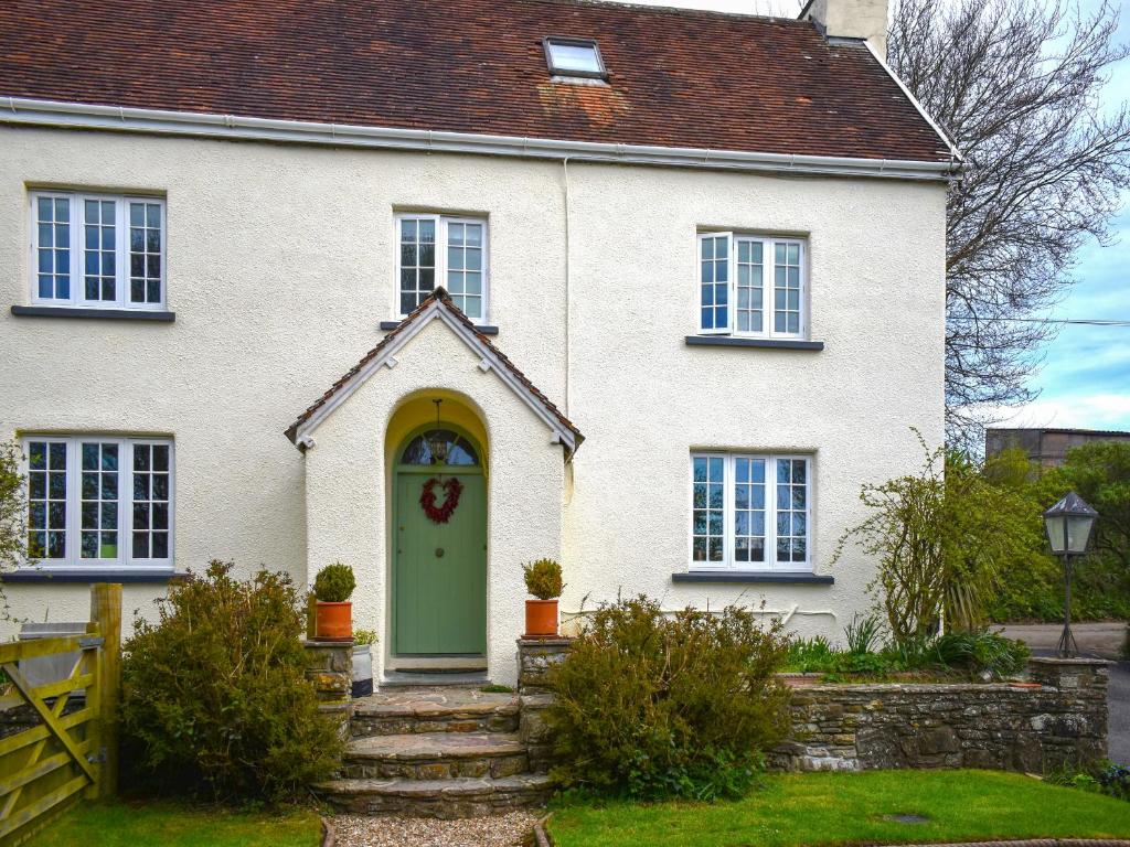 a white house with a green door at Little Gubbs in West Buckland