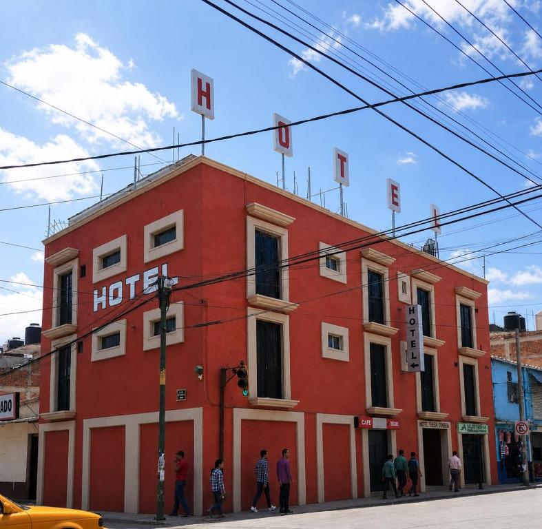 a red building with people standing in front of it at Hotel Bartolomé in Oaxaca City