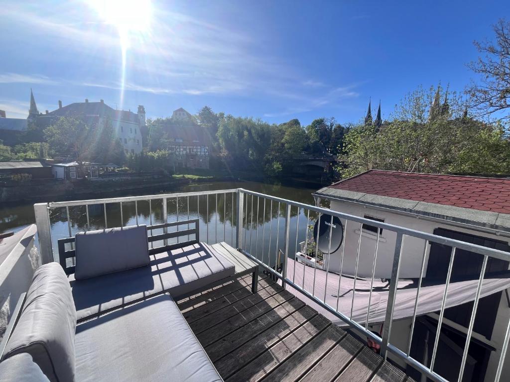 a balcony with a bench and a view of a river at Ferienhaus Domblick Merseburg in Merseburg