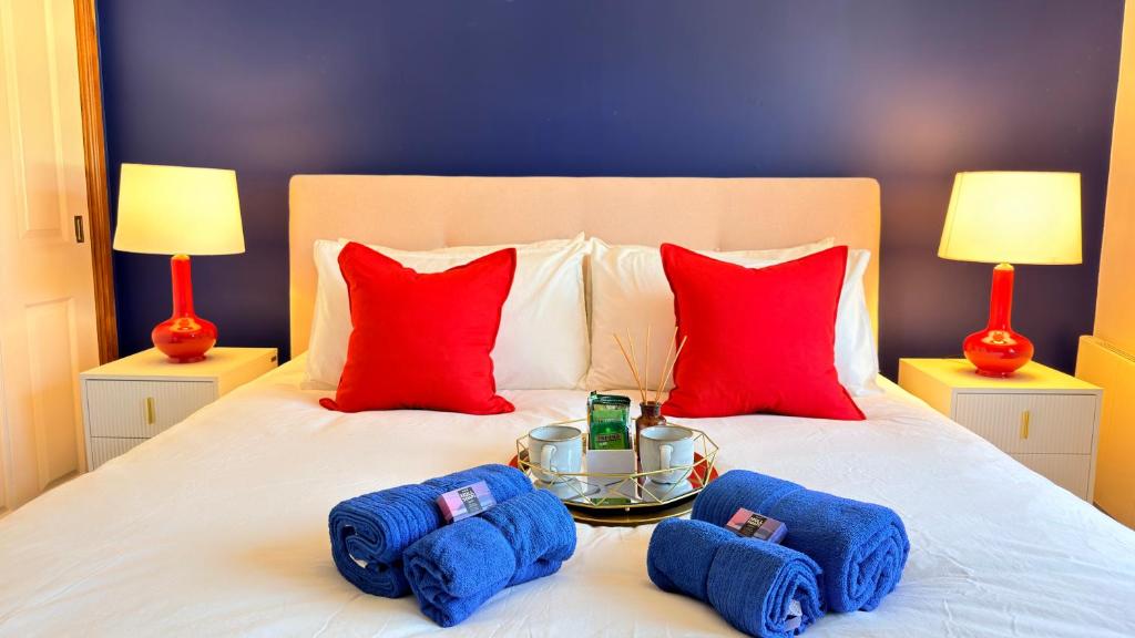 a bed with red pillows and a tray with blue towels at Super-King Room Tobermory with shared bathroom in Tobermory