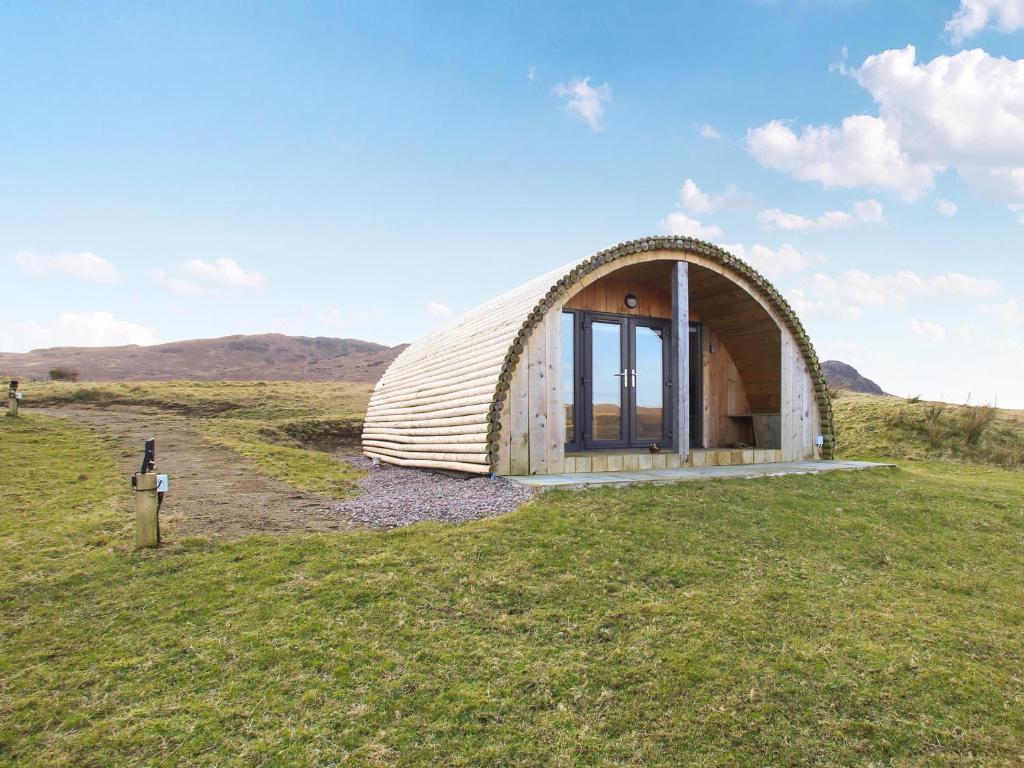 a building with a curved roof on a grass field at Dougie's Pod in Acharacle