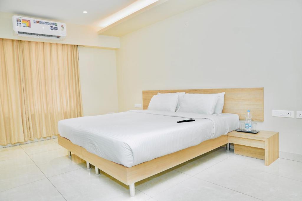 a bedroom with a large white bed and a table at Hotel Shri Ram Residency in Belgaum