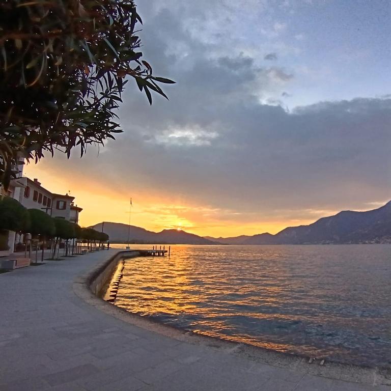 a sunset over a body of water with a pier at La tana del geco in Iseo