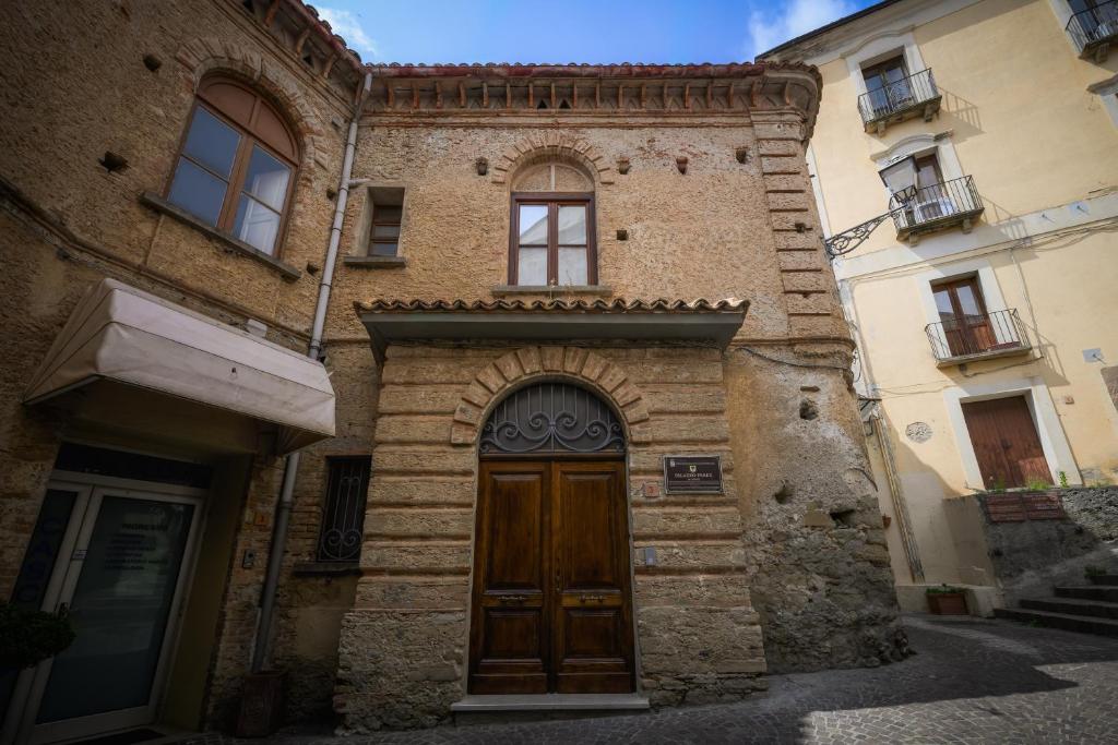 ein altes Gebäude mit einer Holztür an einer Straße in der Unterkunft Palazzo Perez in Belvedere Marittimo