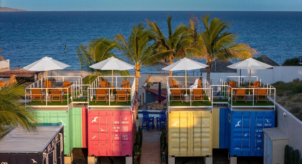 Eine Reihe bunter Container mit Stühlen und dem Meer in der Unterkunft Beach Front Lux Containers in La Ventana