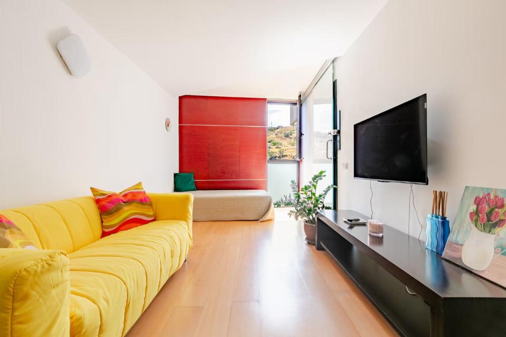 a living room with a yellow couch and a tv at Beach LOFT Tabaiba in Tabaiba