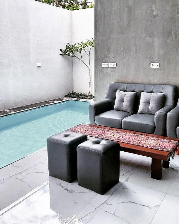 a couch and a coffee table next to a pool at The Yoora Villa in Ngadipuro