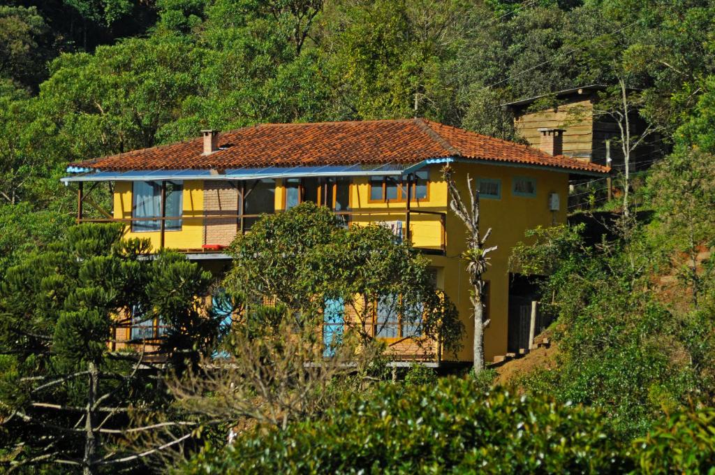 una casa amarilla en la cima de una colina con árboles en Estalagem Terramauá, en Visconde De Maua