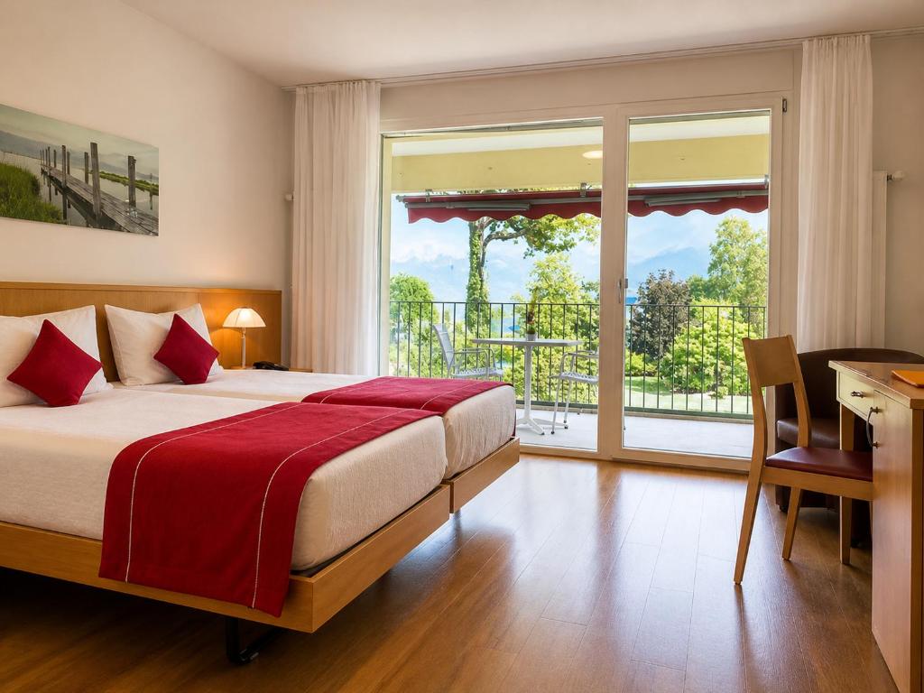 a bedroom with a bed and a desk and a window at Parkhotel Emmaus - Casa del Sole in Ascona