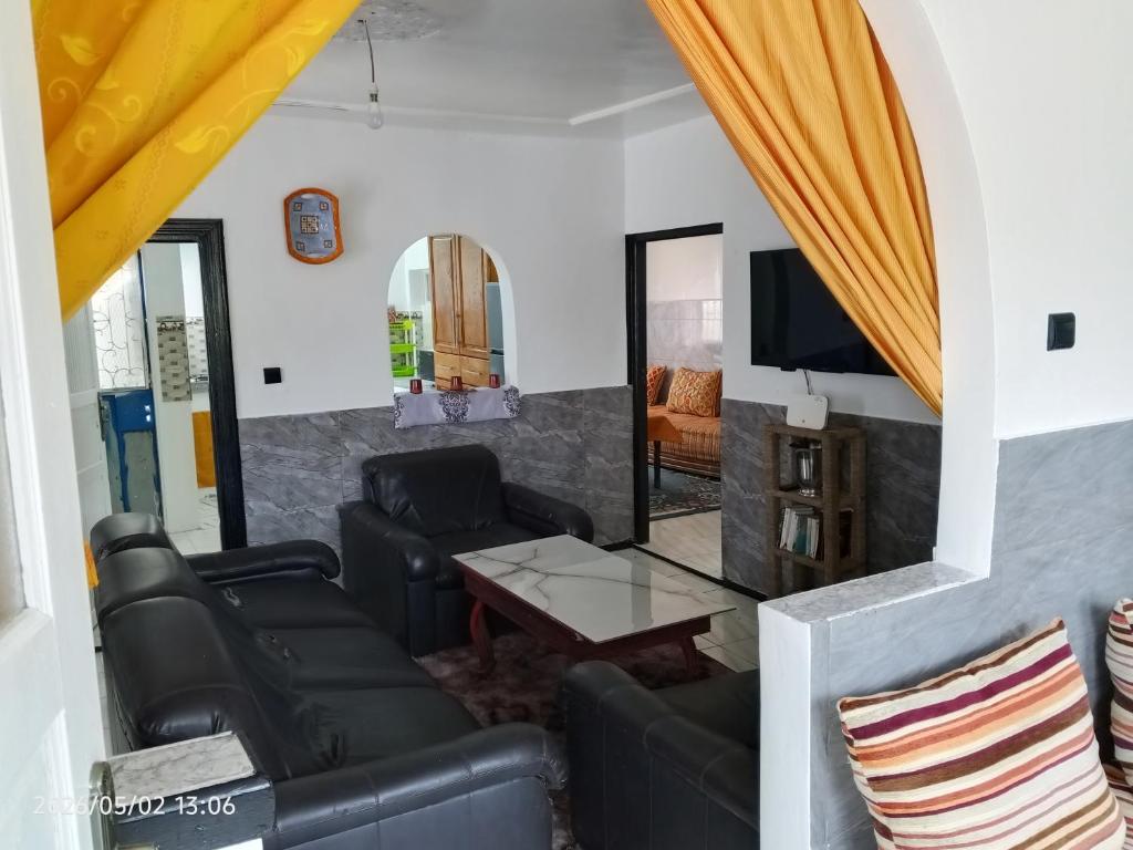 a living room with black leather furniture and a flat screen tv at Cabanon plage david in Bouznika
