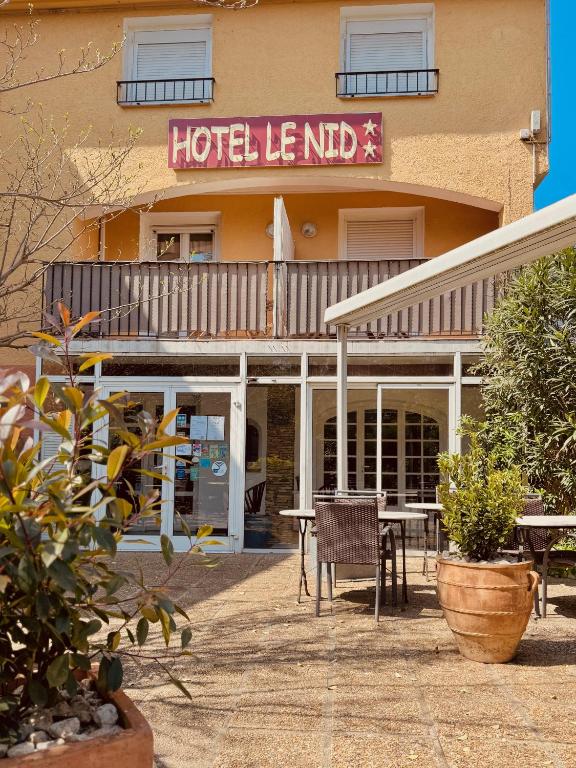a hotel with a table and chairs in front of a building at Hôtel le Nid in Argelès-sur-Mer