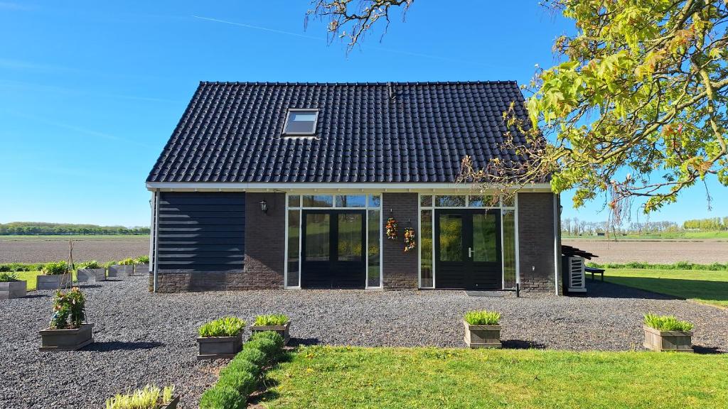 a house with a black roof on a gravel driveway at UNESCO de Beemster, vakantiewoning in Noordbeemster