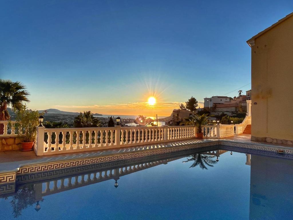 a swimming pool with a sunset in the background at Villa Cala Encantada Sea View Apartments with Pool in Calpe