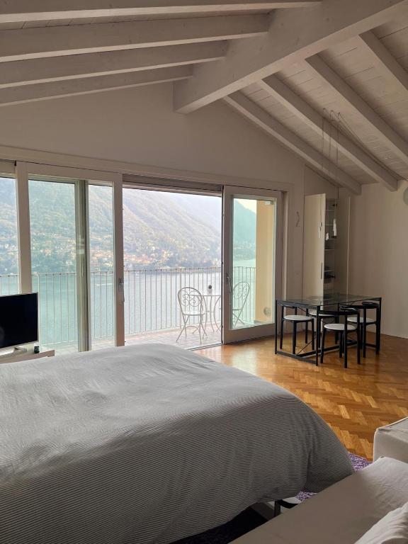 a bedroom with a bed and a balcony with a table at Dream View Lake Como in Carate Urio