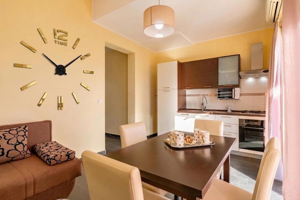 a living room with a table and a clock on the wall at D&A Apartments in Vela Luka