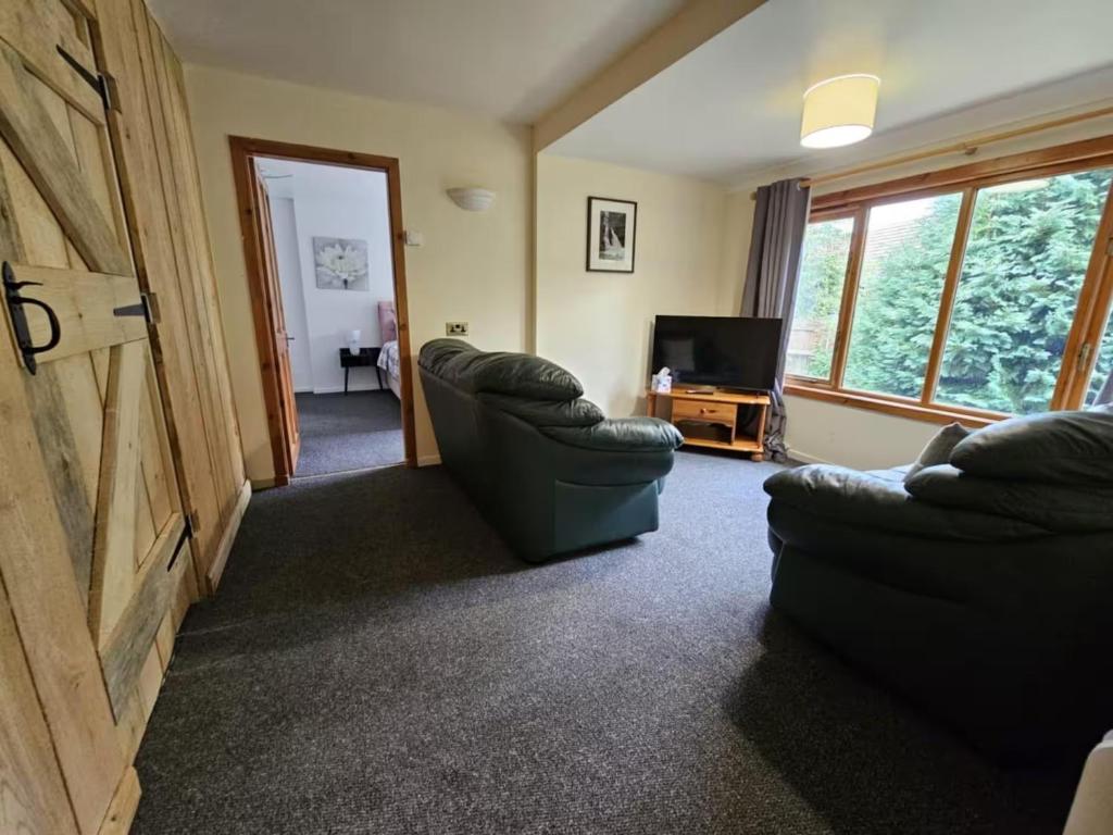 a living room with two chairs and a television at Cottage - Sleeps 5 - Garden - River Side in Garve