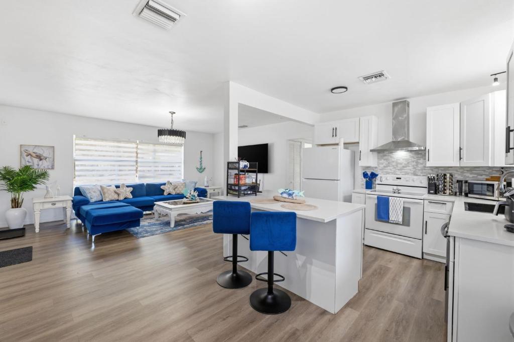 a kitchen and living room with white cabinets and blue chairs at Clearwater Paradise w Hot Tub-Backyard Bliss Near Beach & Hot Spots in Clearwater