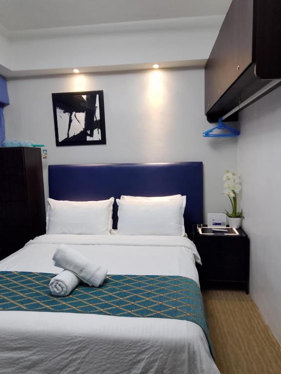 a bedroom with a large bed with a blue headboard at R2 condotel tower in Manila