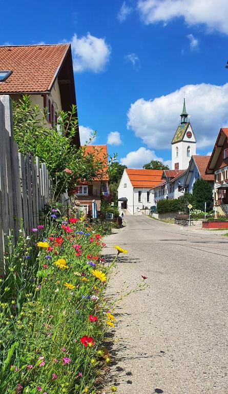 a village with a church and flowers on the side of the road at Ferienwohnung Dorfleben in Weiler-Simmerberg