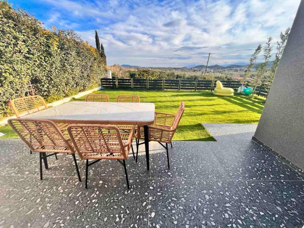 a table and chairs on a patio with a garden at Nafos Villa Stella in Levkákia